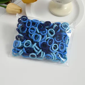 Close-up view of small blue seamless elastic hair ties in a clear plastic packaging bag.