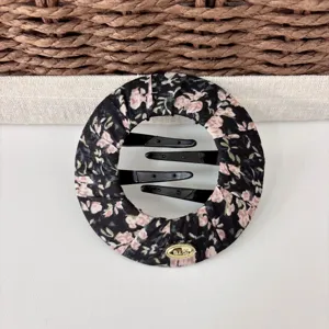 Close-up of black floral fabric hair bun maker with multi-tooth comb and metallic logo.