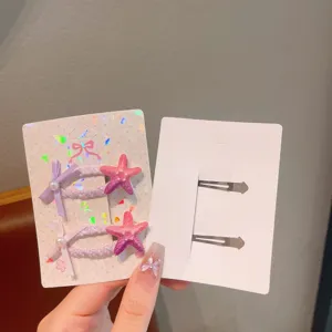 Close-up detail of colorful children's hair clips featuring cute starfish and pearl bows on card.