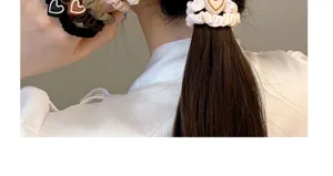 Close-up view of elegant hair scrunchies with cute heart charms, worn in a neat ponytail.