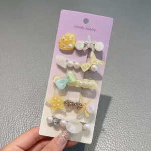 Ocean style hair clip set detail showing cute seashell and pearl designs on purple card.
