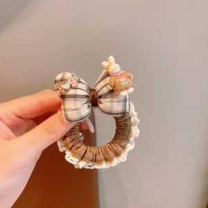 Close-up detail of the brown plaid hair scrunchie with cute lace trim and lovely bunny charm.