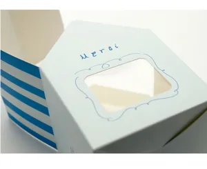 House shaped paper gift box detail with blue stripe roof, window and merci print.