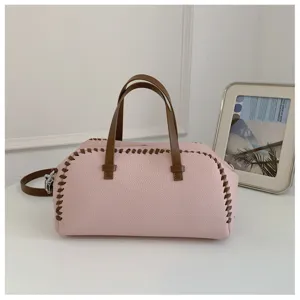 Detail du sac boston en cuir rose avec poignees marron et coutures decoratives style.