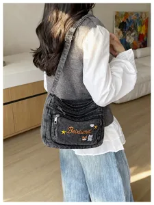Multi-compartment denim crossbody bag featuring cute cat embroidery and casual style for women.