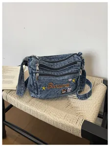 Detailed view of the cute embroidered denim crossbody bag with multi-zipper compartments.