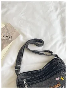 Detailed view of the stylish denim shoulder bag featuring cute embroidery and multiple compartments.