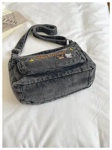 Detailed view of the stylish distressed denim cross-body bag with cute cat embroidery.