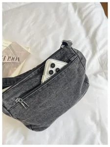 Detail view of stylish multi-compartment denim crossbody bag featuring a front zipper pocket.