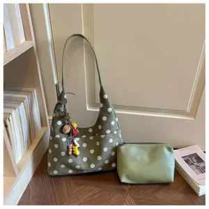 Detailed view of the chic green polka dot hobo shoulder bag with matching pouch and charms.