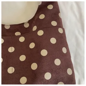 Close-up detail of a brown suede shoulder bag featuring classic cream polka dot pattern.