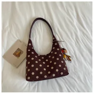 Brown suede polka dot underarm shoulder bag detail showing texture, strap and charm pendant.