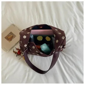 Top-down detail of brown polka dot suede shoulder bag, showing interior and accessories.