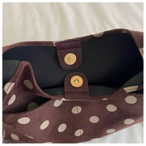 Detailed view of the brown polka dot suede shoulder bag interior and magnetic snap closure.