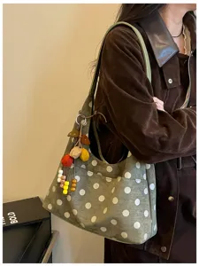 Close-up view of the chic olive green polka dot shoulder bag featuring cute charms and style.