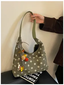 Detailed shot of green polka dot suede hobo bag with playful charms and stylish shoulder strap.
