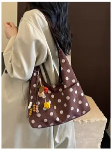 Brown polka dot shoulder bag detail, vintage suede style hobo bag with cute charm decoration.