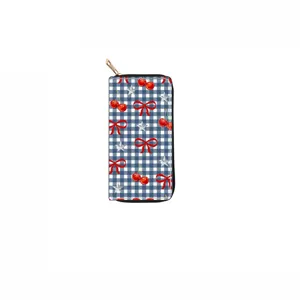 Detailed view of long zip wallet featuring cute blue gingham check, red cherry and bow print.
