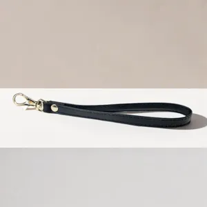 Zwarte PU lederen polsband met goudkleurige karabijnhaak voor portemonnees en clutches.