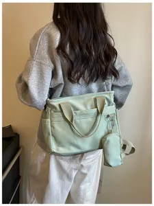 Sac bandoulière décontracté en toile avec petite pochette, idéal pour un usage quotidien.