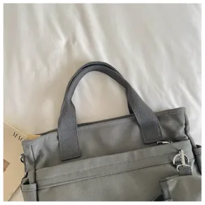 Détail sac bandoulière en toile grise, cabas décontracté avec poches multiples.