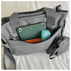 Sac bandoulière en toile décontracté vue détaillée avec un espace de rangement pratique.