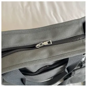 Gros plan de détail sur le sac cabas en toile grise avec fermeture éclair argentée et tissu.