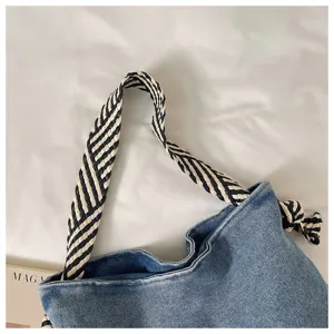 Dettaglio della borsa a spalla in denim con tracolla intrecciata nera e bianca e tessuto.