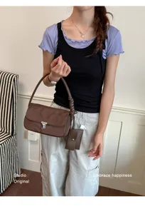 Stylish brown shoulder underarm bag with metal lock and small pouch for women daily use.