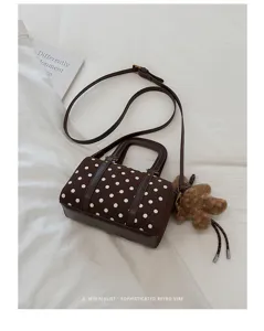 Vue rapprochée et détaillée du sac bandoulière chic à pois bruns avec joli charm ours.