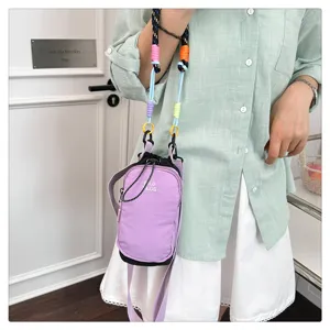 Detail view of a stylish purple crossbody phone bag with colorful woven strap for outdoor use.