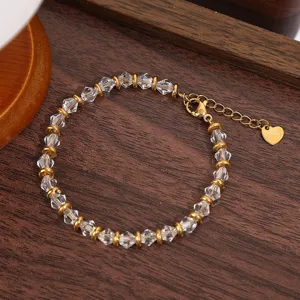 Close-up detail of clear faceted crystal and gold metal bead bracelet with extension chain.