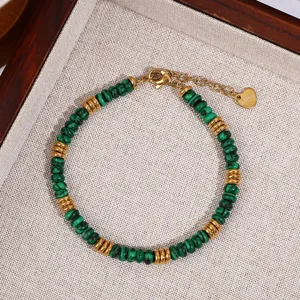 Closeup of green malachite bead bracelet with gold metal spacer discs and heart steel tag.
