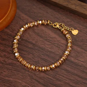 Gold-colored metal and amber crystal beaded bracelet with heart charm for women, detail shot.