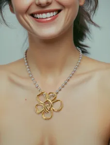 Primo piano della collana bicolore con perline e ciondolo a fiore dorato irregolare.