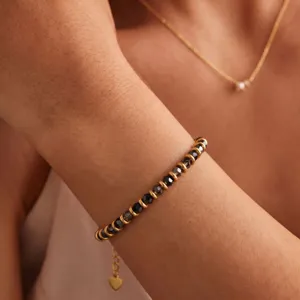 Gold beaded bracelet with black crystal cut beads and heart charm detail for women