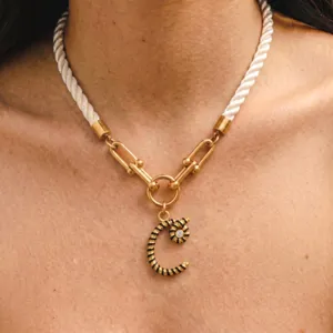 Primo piano della collana con ciondolo a lettera e corda intrecciata stile di design.