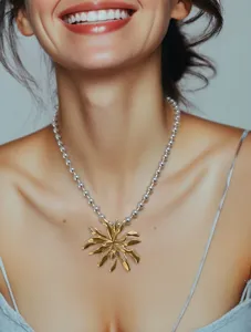 Primo piano di una collana bicolore in acciaio inox con perline argento e ciondolo solare.