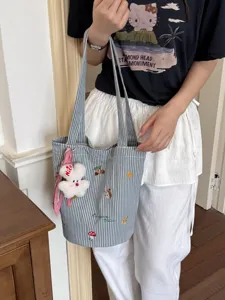 Niedliche gestreifte Canvas-Stofftasche mit Stickerei und Plüschtier-Anhänger für Damen.