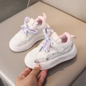 Close-up view of children's white casual sneakers with colorful laces and pink lining details.