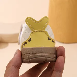 Chaussures bébé premier pas détail arrière avec queue 3D jaune mignonne et semelle marron.