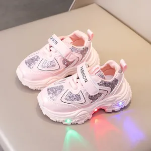 Close-up of pink children light-up sneakers with glitter details and convenient velcro straps.
