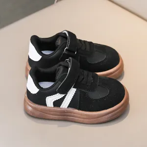 Detailed view of children's black and white casual sneakers with brown soles and velcro straps.
