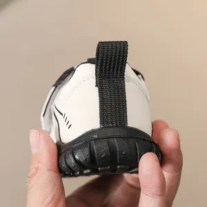 Detailweergave peuter stapschoenen, ademende zachte zool kinderschoenen in wit en zwart design.