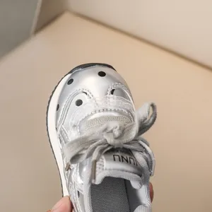 Détail basket enfant argentée métallisée, lacets gris, semelle blanche chaussure mode.