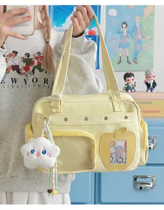 Detailed view of light yellow canvas pain bag with clear pocket and cute plush pendant.