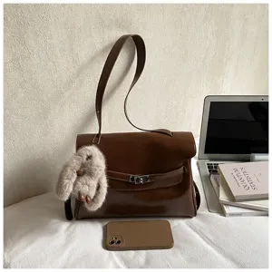 Vue détaillée du sac porté épaule Kelly en cuir marron avec charm lapin peluche mignon.