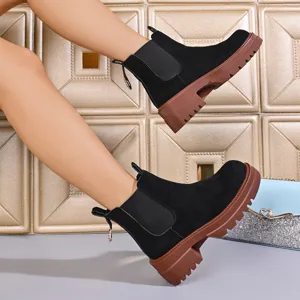 Detail shot of women's black Chelsea boots with chunky brown platform soles and elastic side panels.