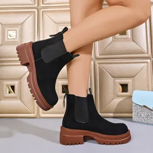 Detail shot of women black suede Chelsea boots with chunky platform lug sole worn by model.