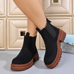 Detail view of black platform chelsea boots showing textured suede and chunky rubber lug sole.